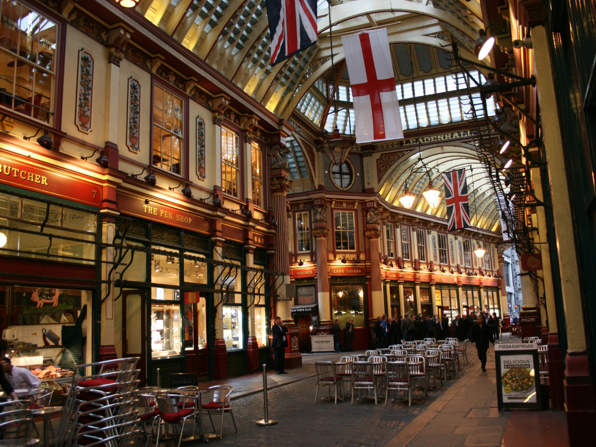 Indoor Market in London with glass ceilings. UK Flag and English Flag are hanging from the roof with shops down below.