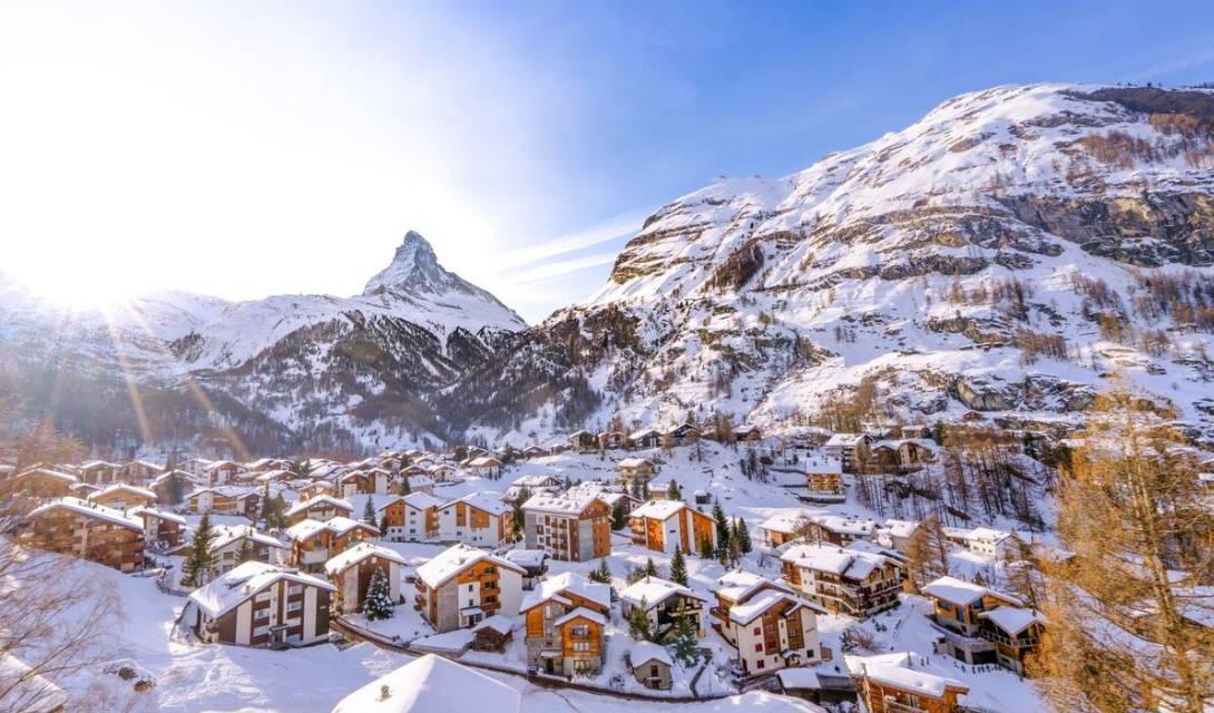 Snow-covered Albinen village nestled in the Swiss Alps during winter with clear blue skies and a mountain background